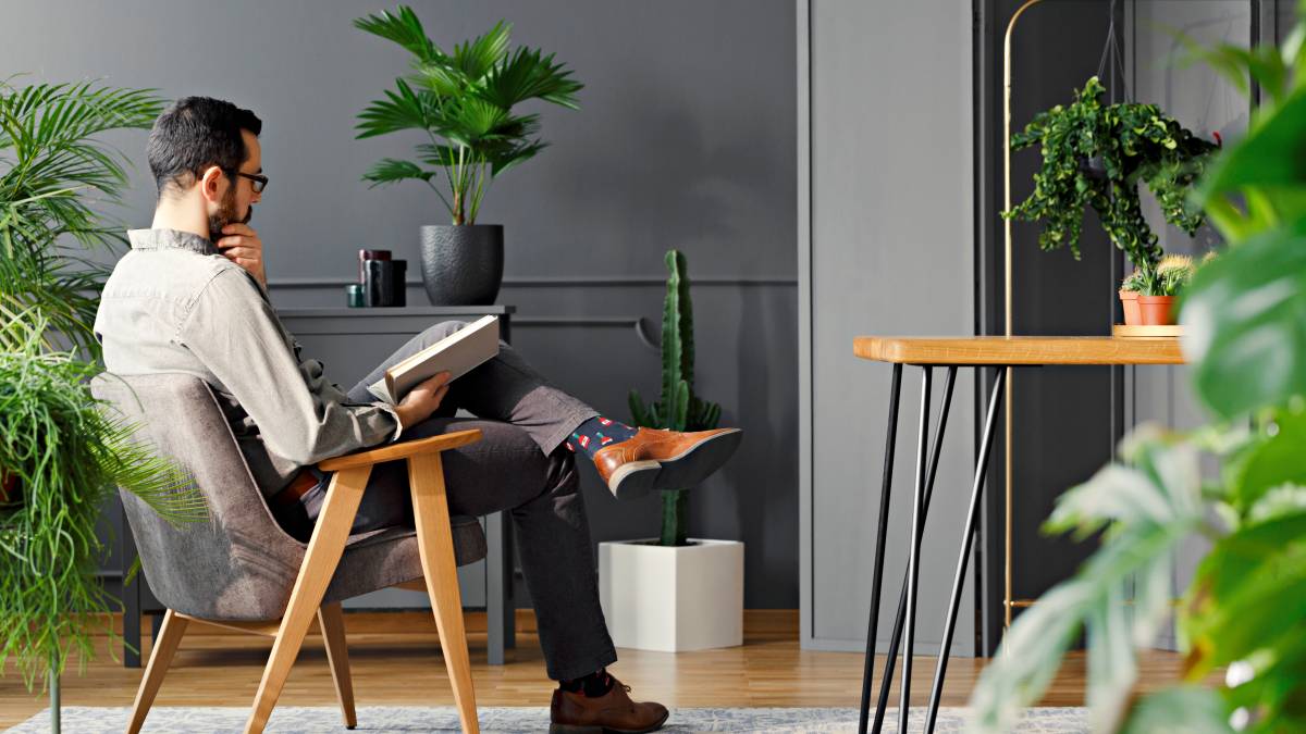 man reading book in garden room