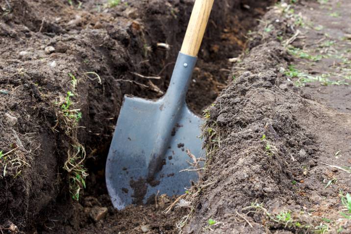 digging a trench with a shovel before laying sleepers for garden edging 