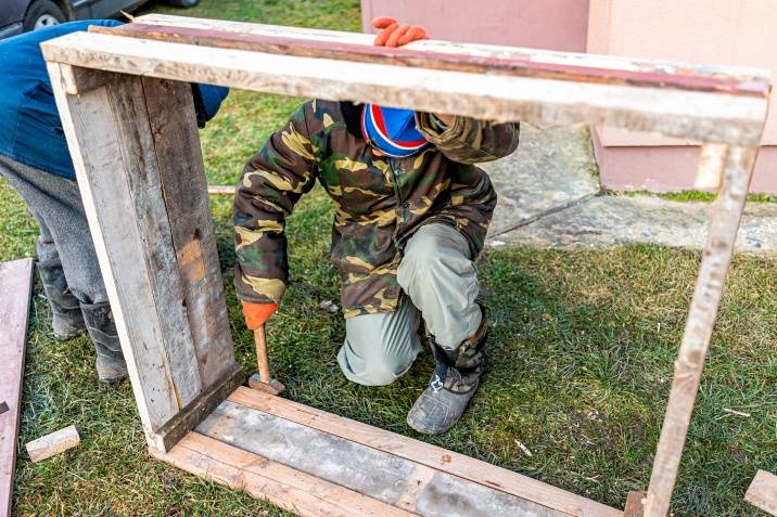 two people building a rectangular garden bed with wooden sleepers