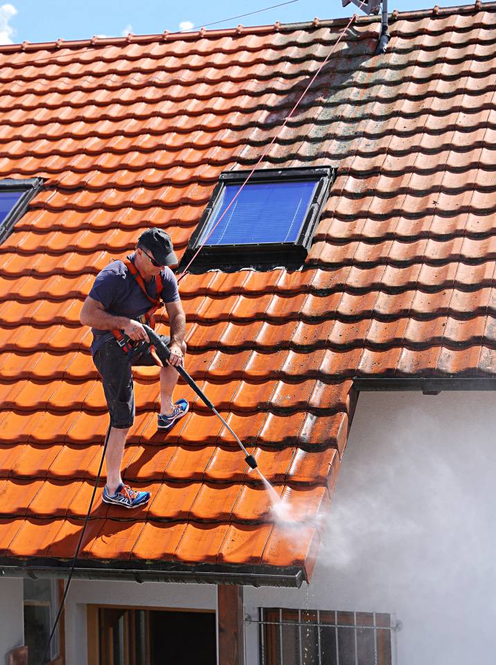 a man using a pressure washer to clean a roof