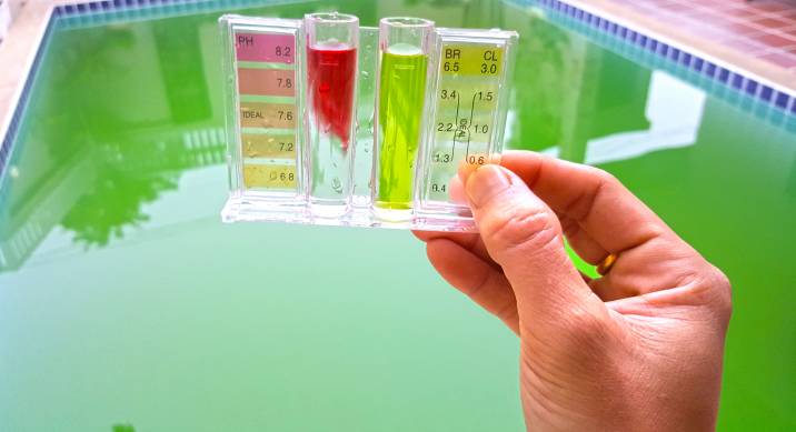 checking pH level of a green swimming pool with a pH metre
