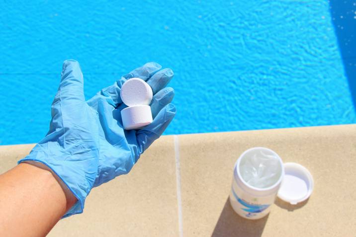 white chlorine tablets in the hand of a swimming pool service worker for disinfection