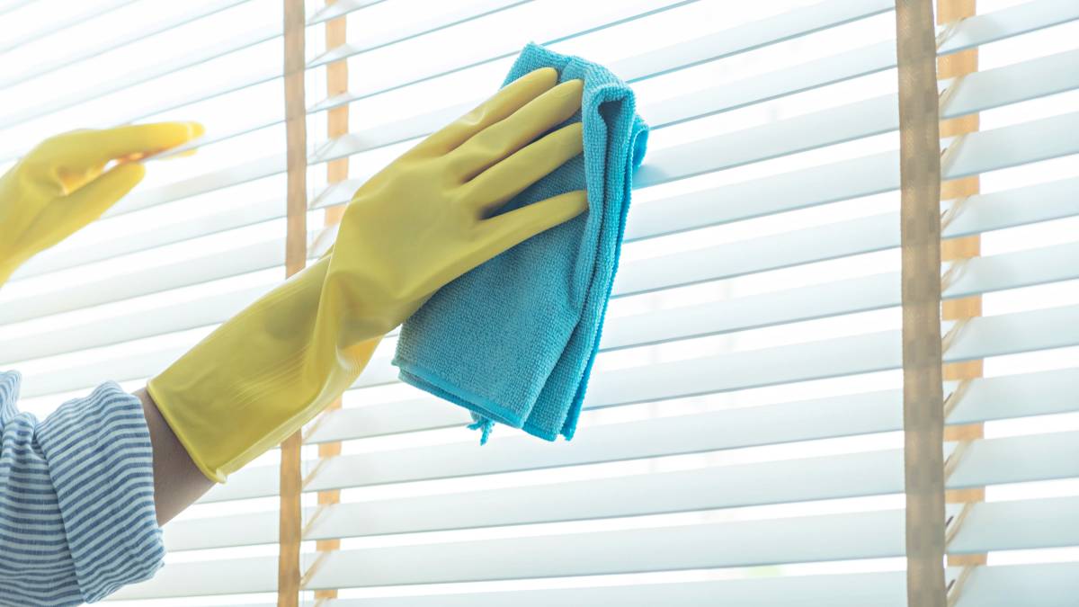 woman cleaning blinds with fiber cloth