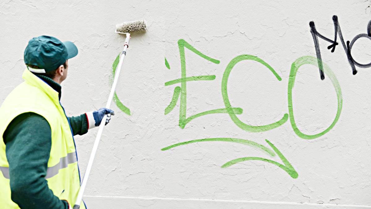 man painting over graffiti
