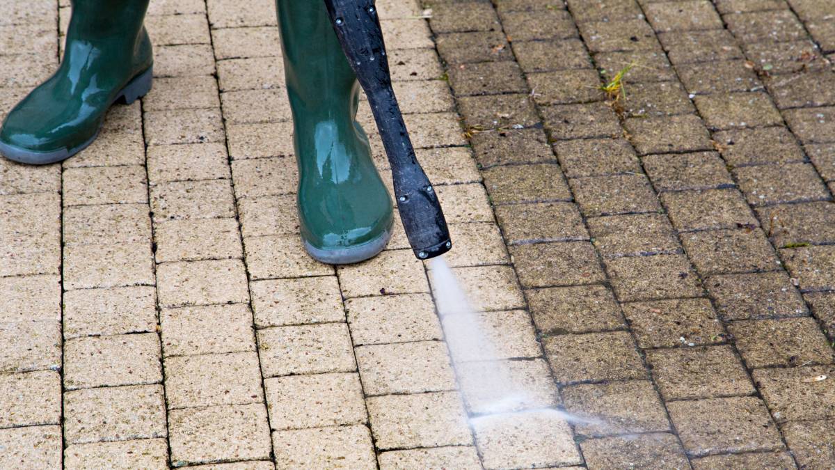 man pressure washing a driveway