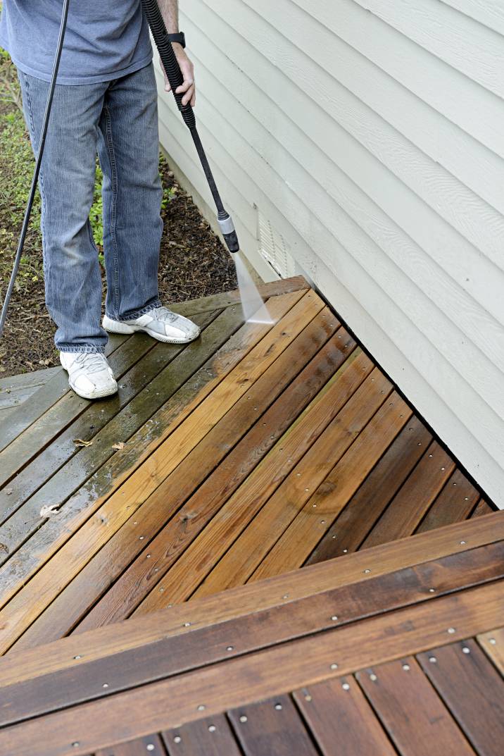 a man pressure washing a deck