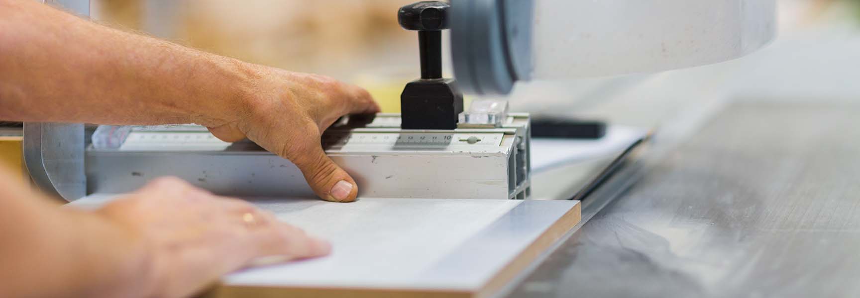 A close-up view of a person using a saw to cut a piece of MDF board, creating a shower niche.