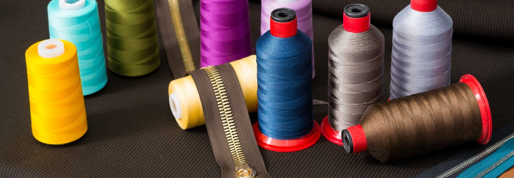 A close-up image of a zipper and different spools of thread.
