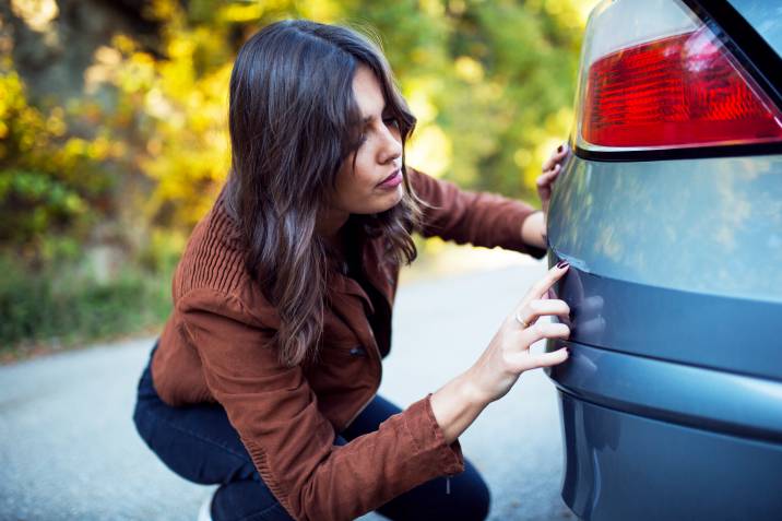 a woman checking a scratch on her car