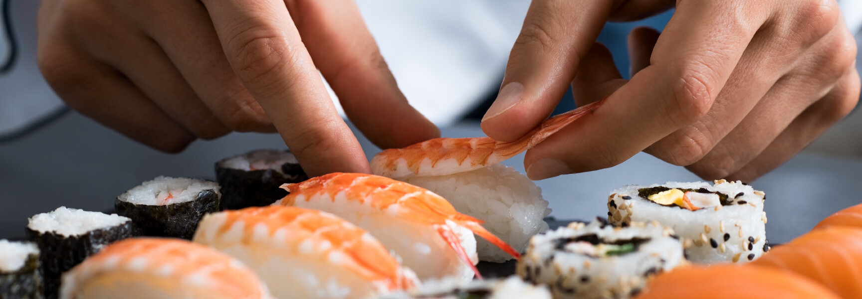 A close-up photo of a tray filled with a variety of colorful sushi rolls, neatly arranged and ready for delivery.