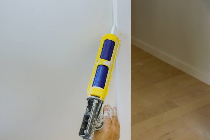 applying painter's caulk to molding trim