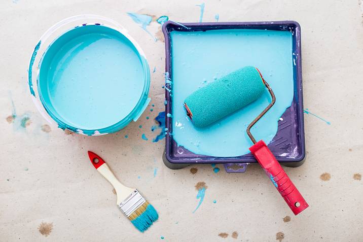 a bucket of blue paint and a brush roller paint tray