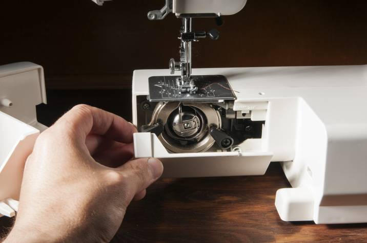 person opening up sewing machine parts to clean