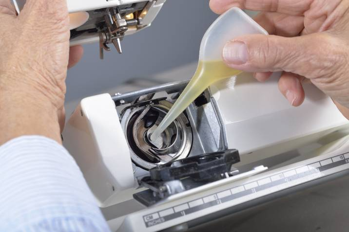 person applying oil to their sewing machine