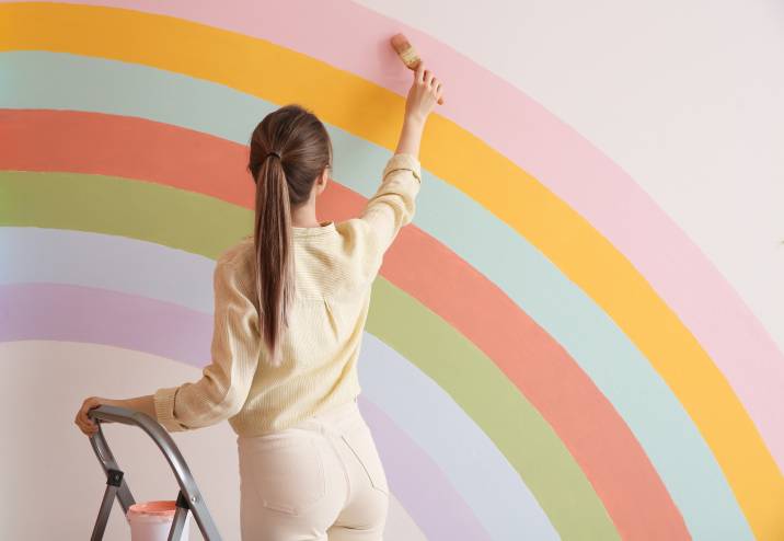 woman painting a wall with rainbow pastel colours