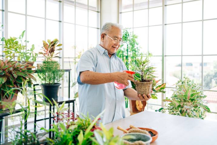 Happy male senior tending to his indoor garden