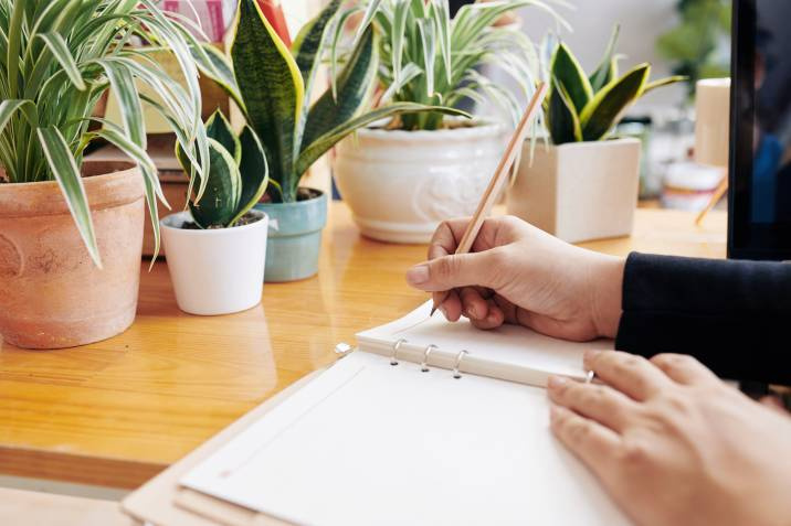 Hands of gardening business owner writing down her plans and ideas in notebook