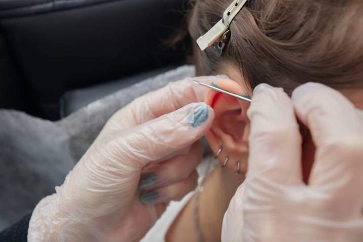 a woman getting an industrial ear piercing