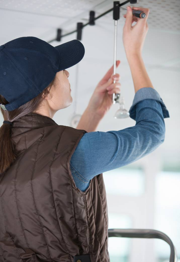 female contractor installing a suspended light, ceiling light fixture