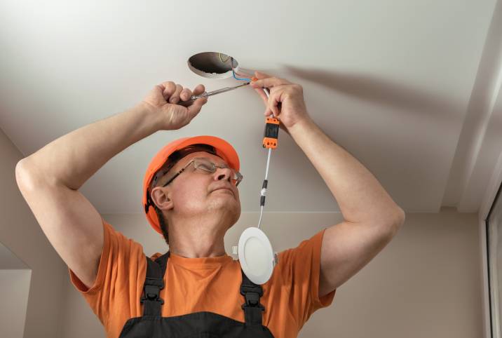 an electrician fixing the wiring for a downlight