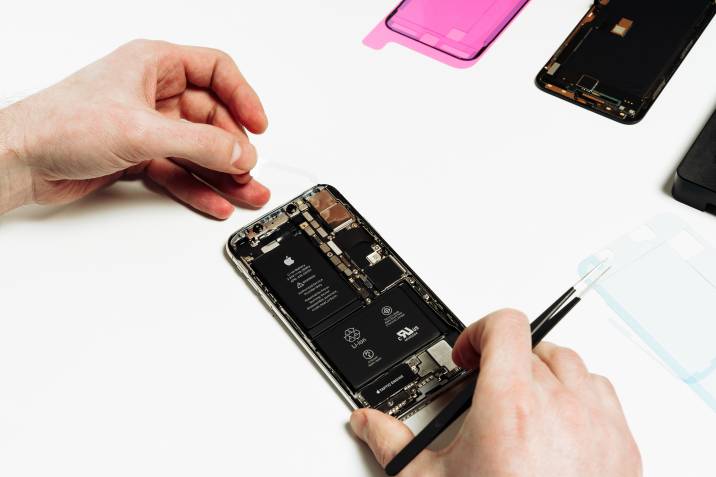 iPhone repair cost - A technician uses precision tools to repair an iPhone, carefully working on the internal components.