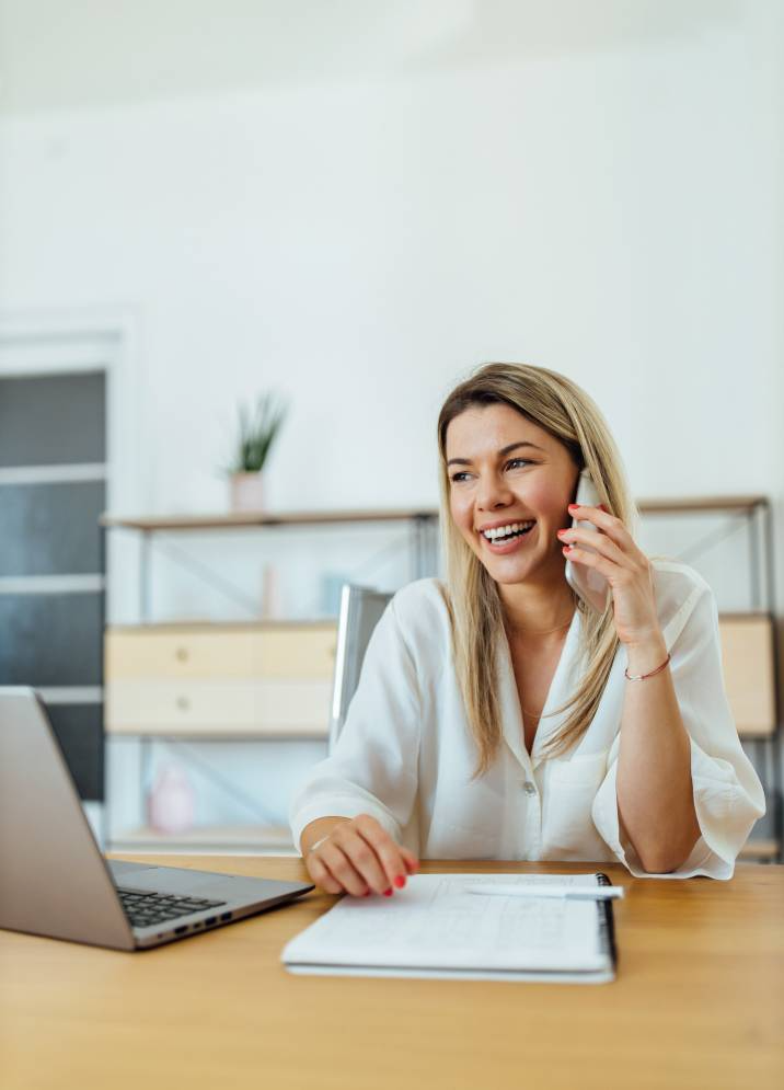 smiling accountant, bookkeeper talking on phone with her client, asking for a referral and testimonial