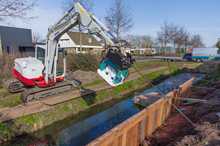 a worker building a retaining wall along a riverbank