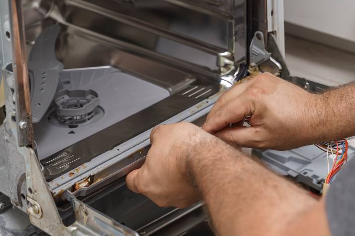 a worker removing a dishwasher's dirty rubber seal 