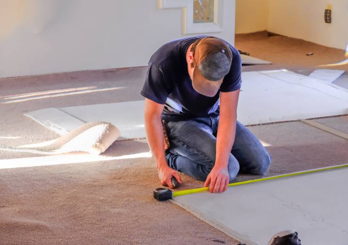 a worker measuring new carpet for installation