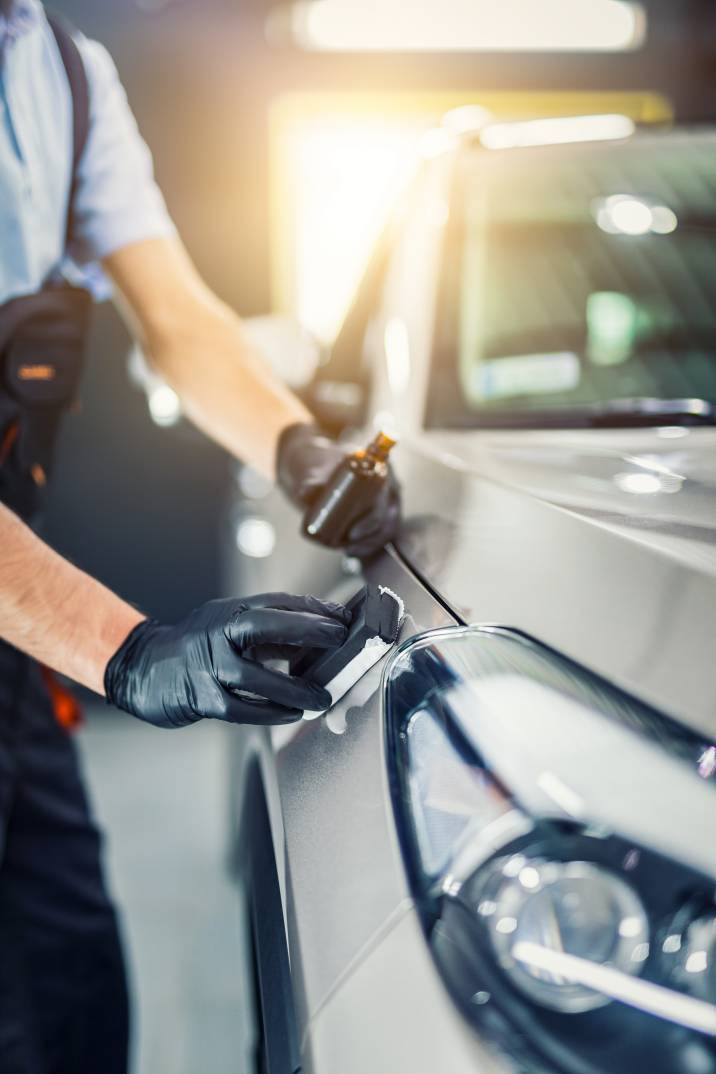 a car detailer coating a vehicle hood