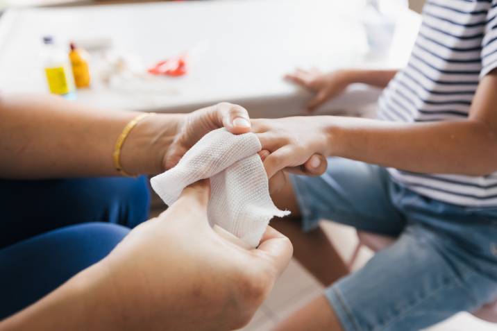 babysitter doing first aid on child with finger injury