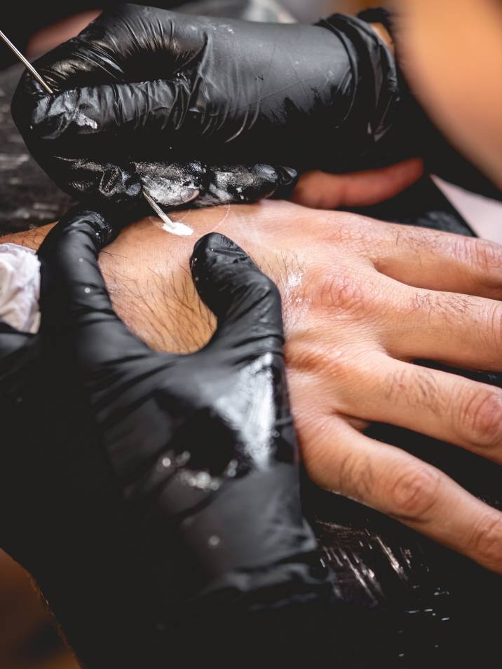 a tattoo artist using hand poke technique to tattoo a client