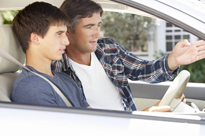 a man teaching a teenager how to drive