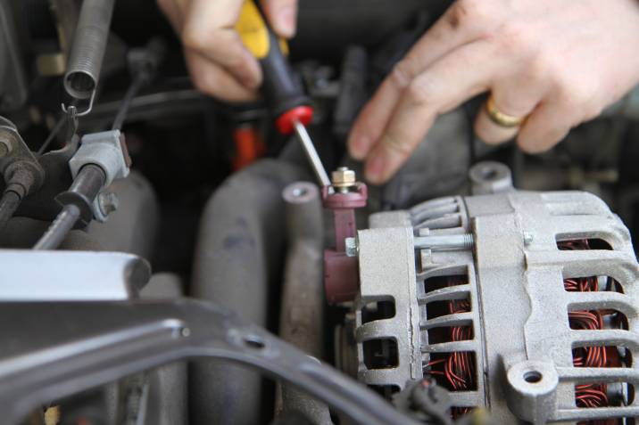 man replacing an alternator in a car