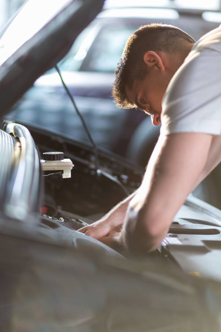 Car service cost - mechanic inspecting a car engine closely