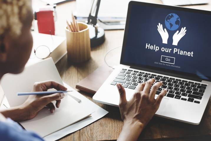 Social worker creating website content as a side hustle. “Help our planet” landing page on laptop