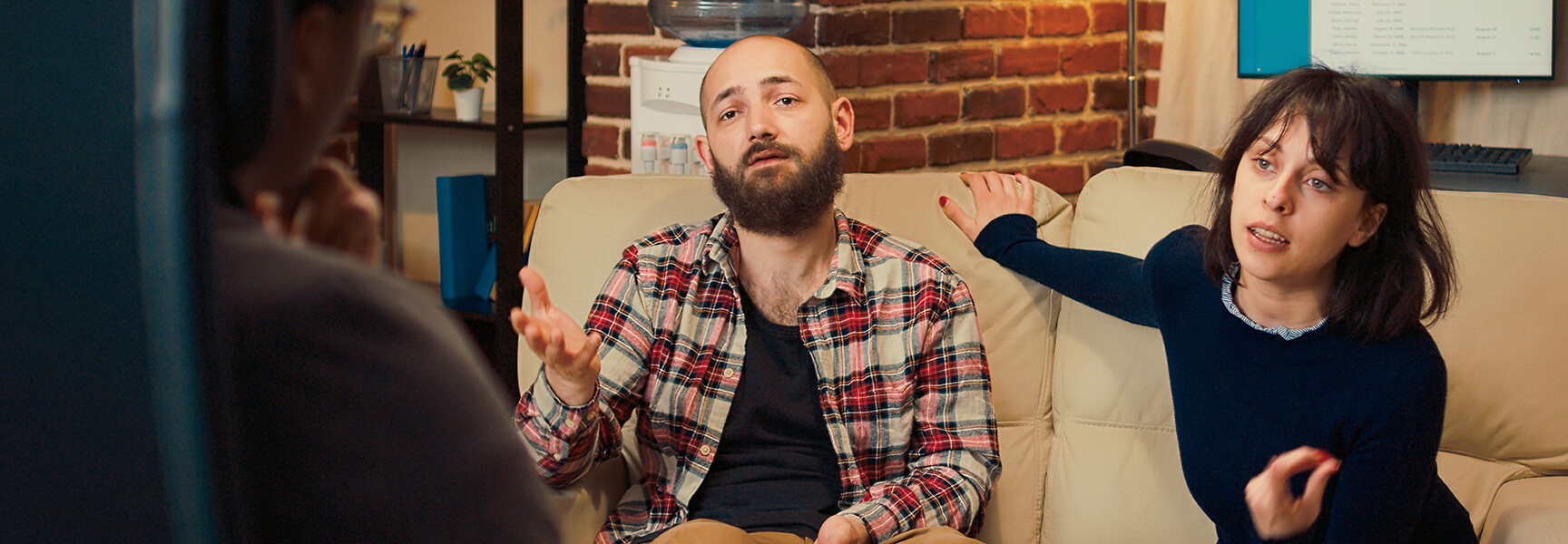 A diverse family sitting during a therapy session, with a therapist leading the discussion and offering support.