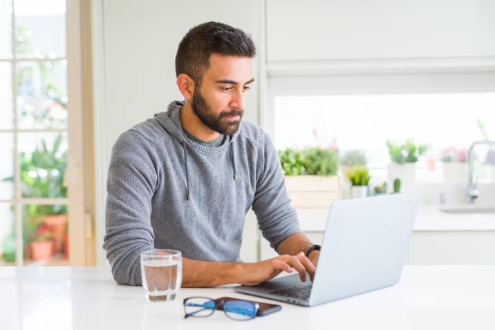 male house sitter using laptop, signing up for house sitting website