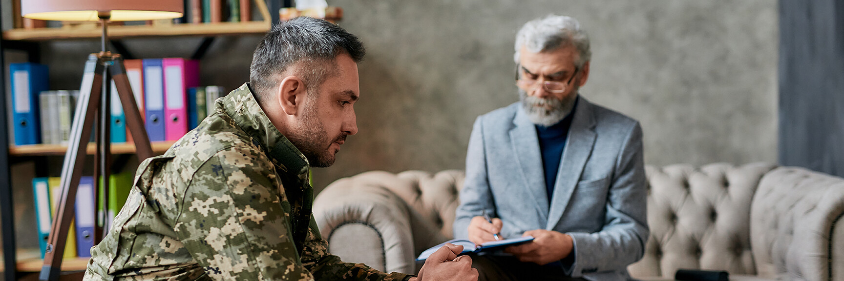 A person sitting in a therapy session, with a therapist listening attentively, providing support for someone with PTSD.