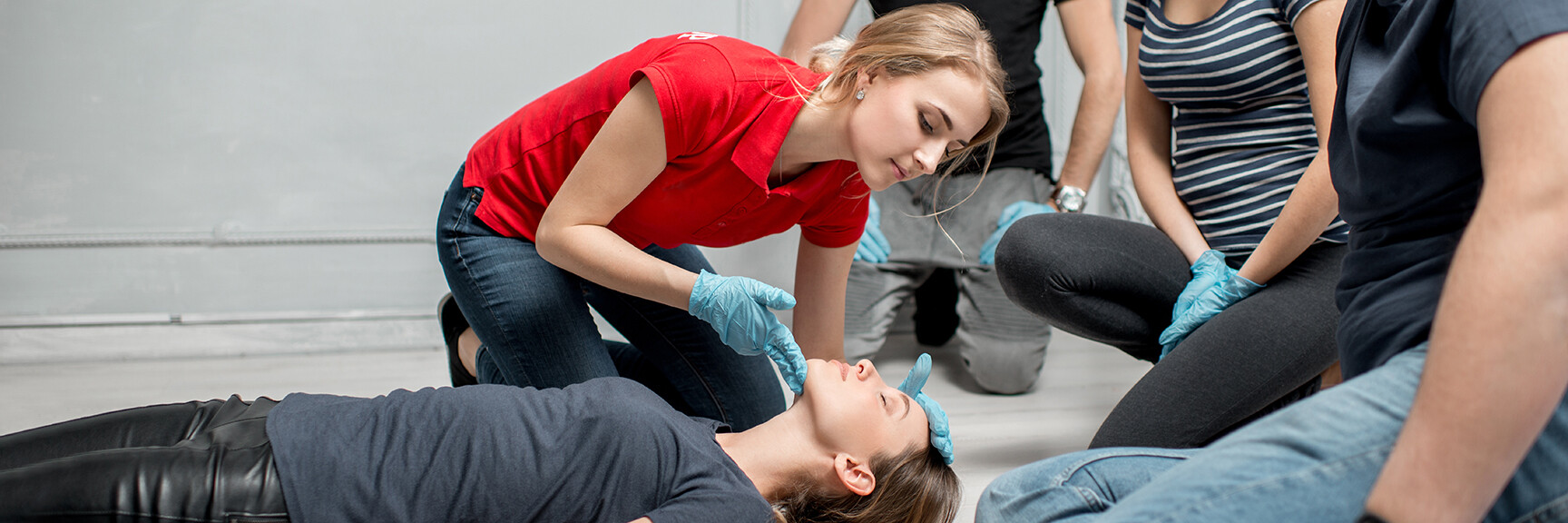 A group of people participating in a first aid training session, learning life-saving techniques and practicing CPR on mannequins.