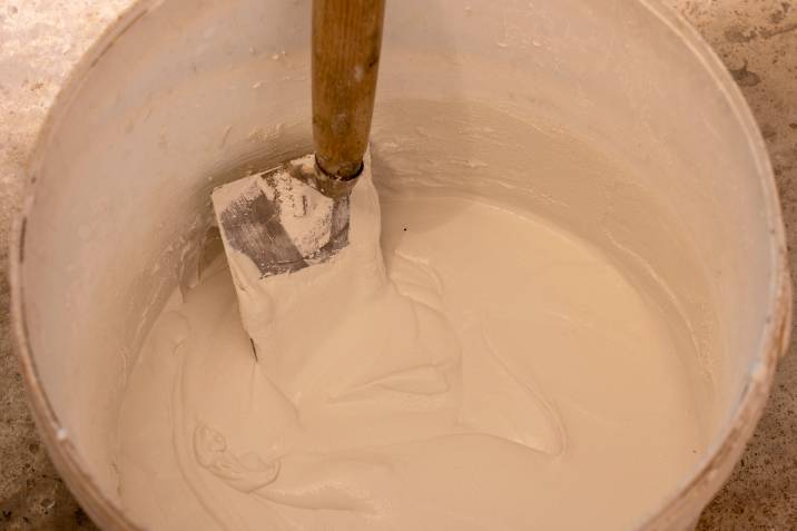 Top view, close up. White poultice and trowel in a bucket. For cleaning light-coloured rocks
