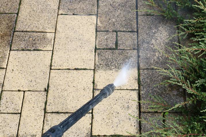 Cleaning dirty paving stones in the garden with a pressure washer