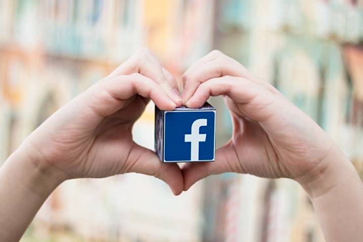 a person holding a cube with a Facebook logo