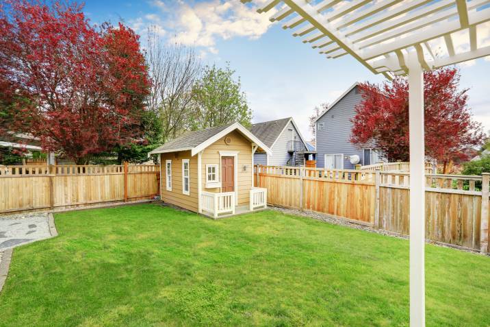 A small wooden shed with a porch, designed to match the surrounding wooden fence