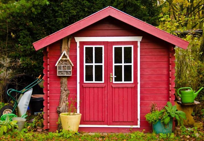 A red wooden shed with white trim around the doors and windows