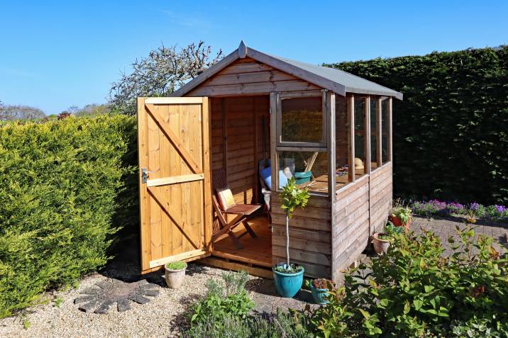 A wooden open-concept shed with large windows and an open door