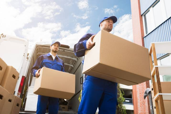 removalists taking heavy boxes out of their truck