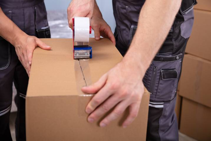 removalist sealing a box with packing tape