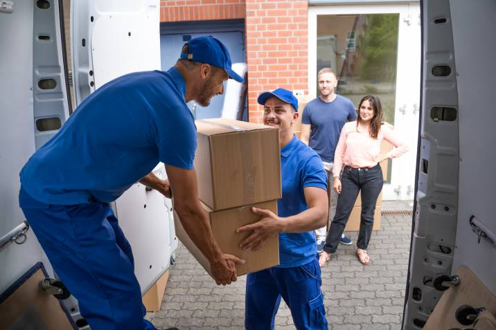 movers helping each other load boxes in their vehicle