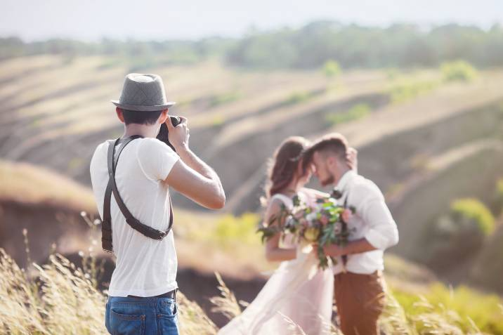 wedding photographer shooting a couple out in the field